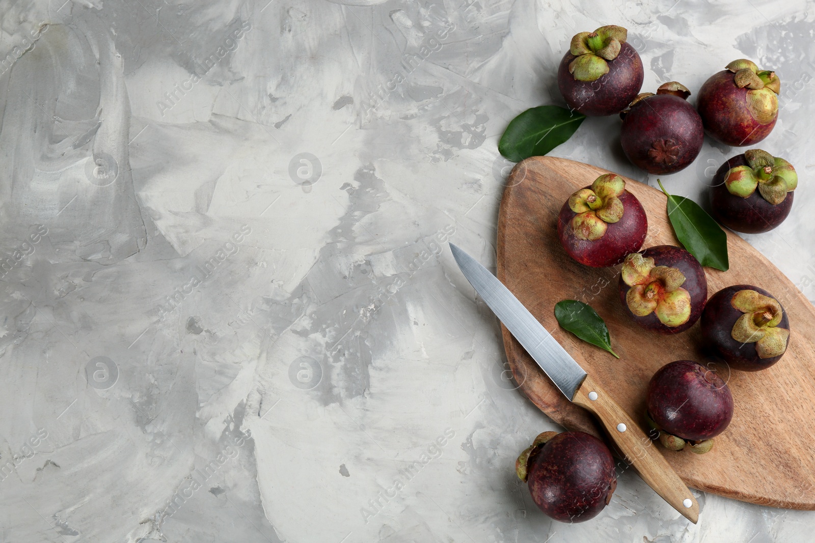 Photo of Fresh ripe mangosteen fruits on light grey table, flat lay. Space for text