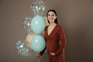 Photo of Happy pregnant woman with balloons near dark wall. Baby shower party