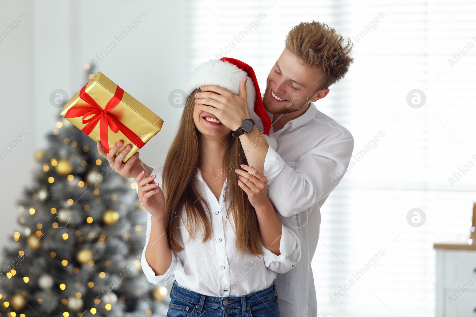 Photo of Young man giving Christmas gift to his girlfriend at home