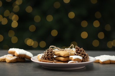 Photo of Decorated cookies on grey table against blurred Christmas lights