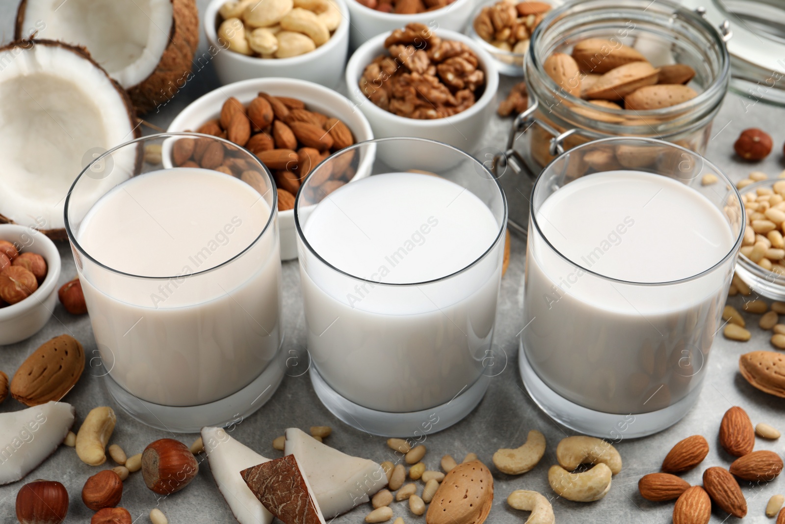 Photo of Vegan milk and different nuts on grey table