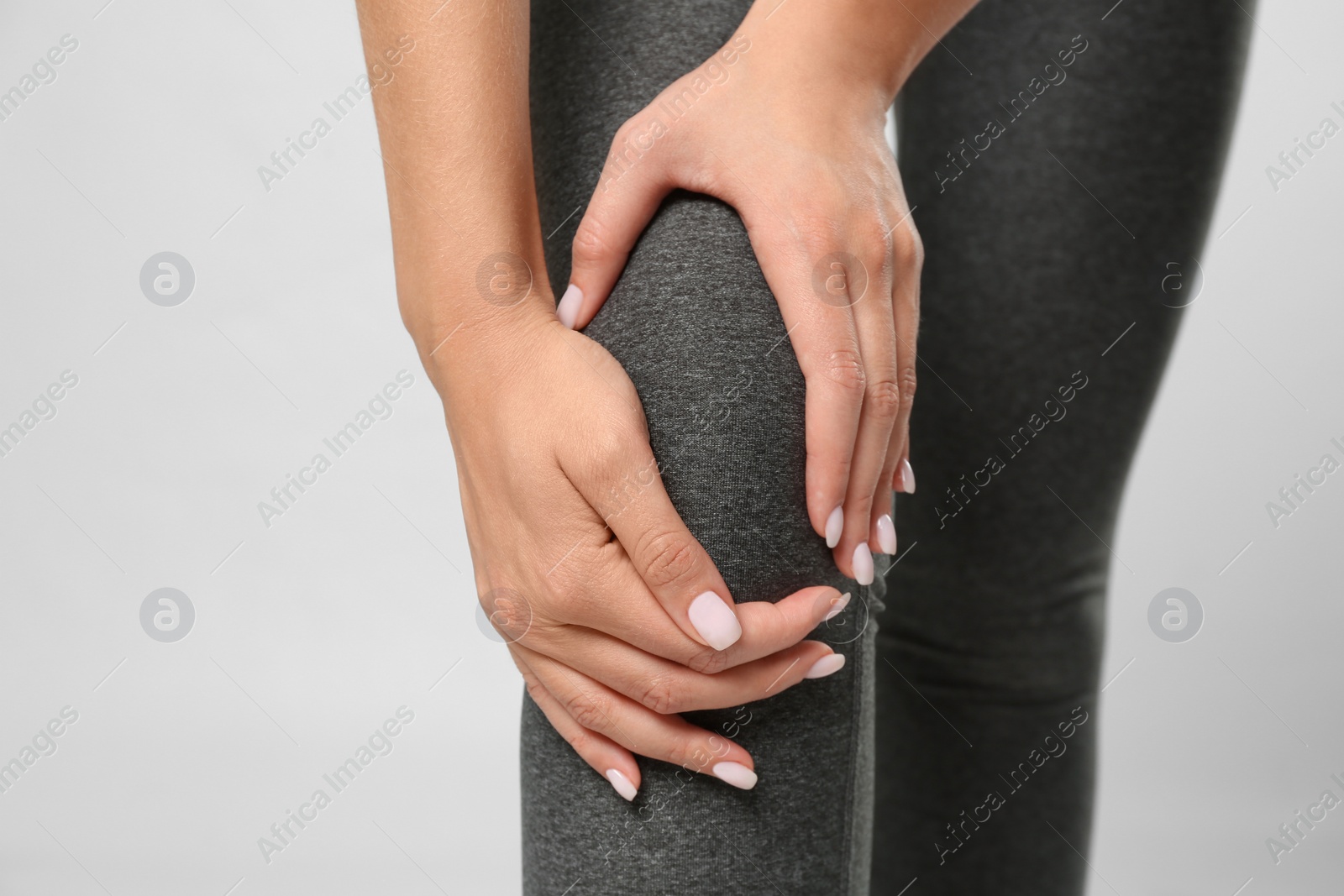 Photo of Woman having knee problems on grey background, closeup