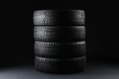 Photo of Stacked winter tires on black background. Car maintenance
