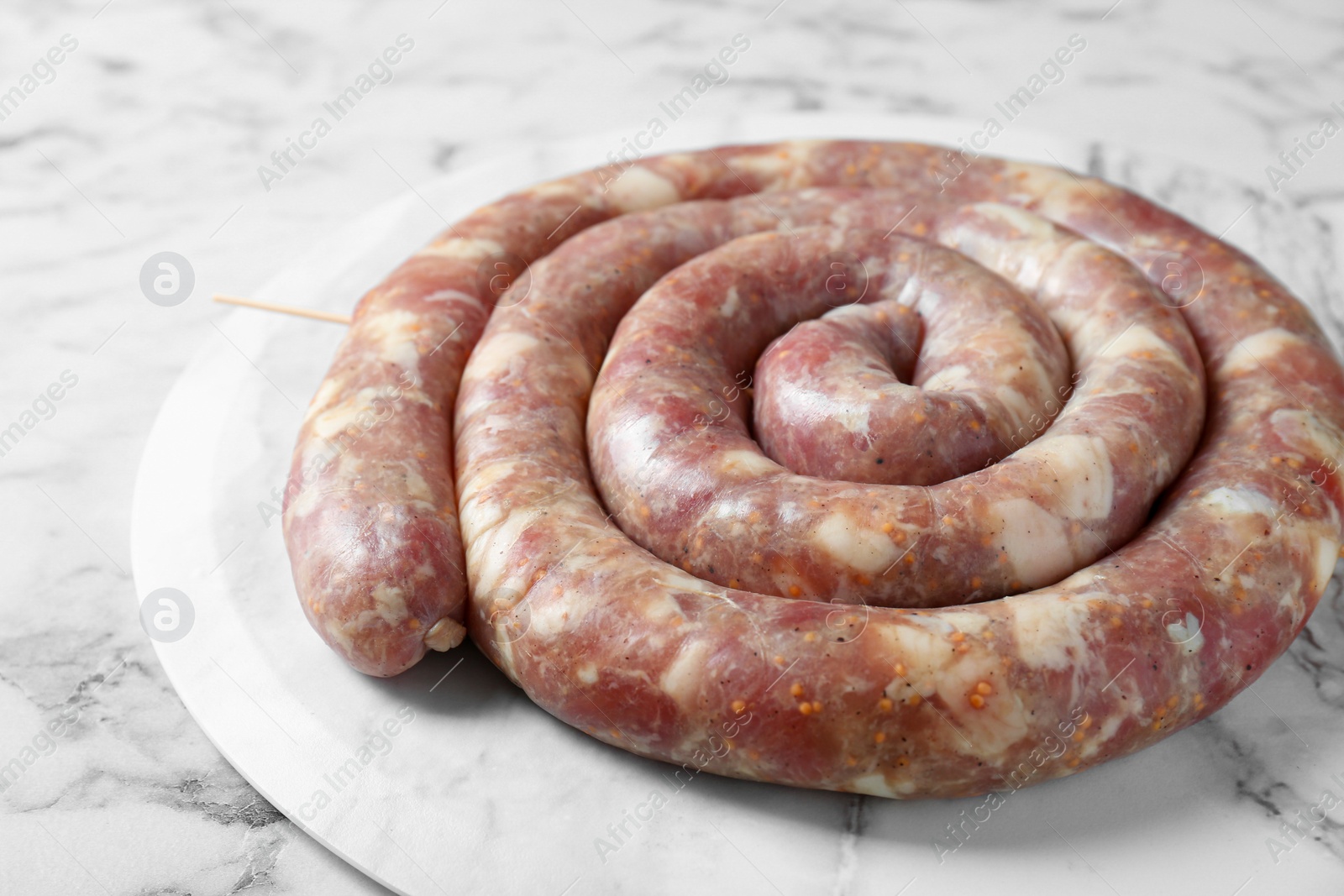 Photo of Raw homemade sausage on white marble table, closeup