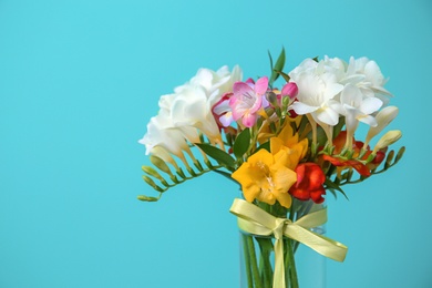 Photo of Glass vase with beautiful freesia on color background