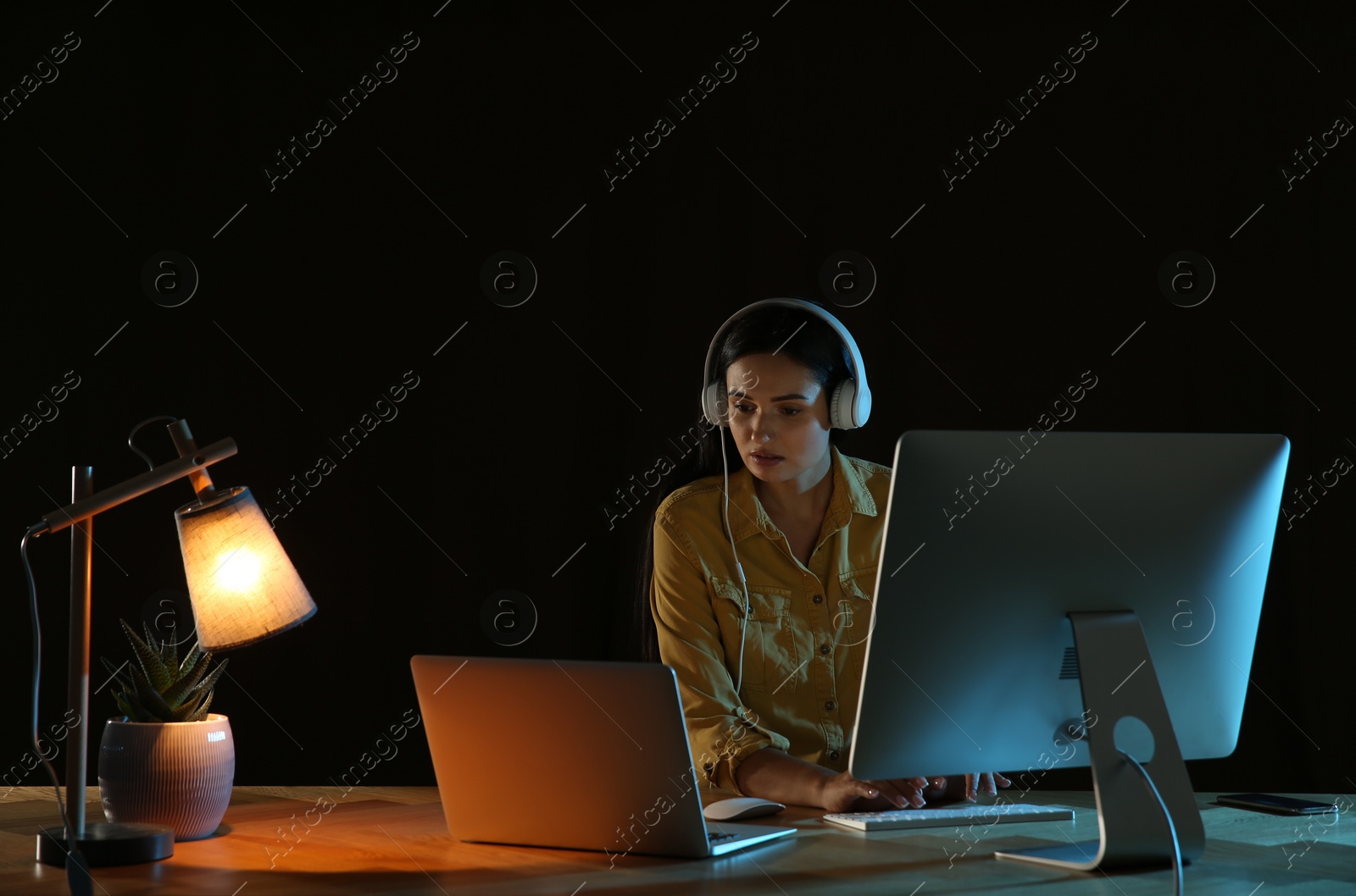 Photo of Programmer with headphones working in office at night