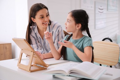 Photo of Mother helping her daughter doing homework with tablet at home