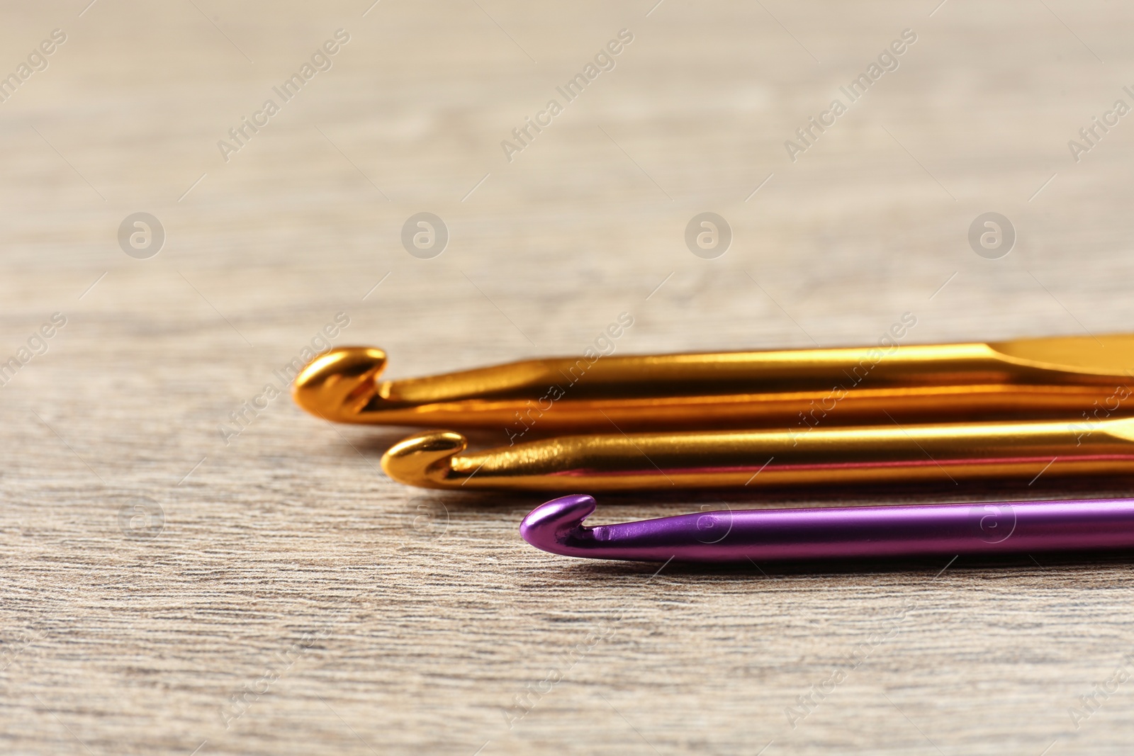 Photo of Many crochet hooks on wooden table, closeup