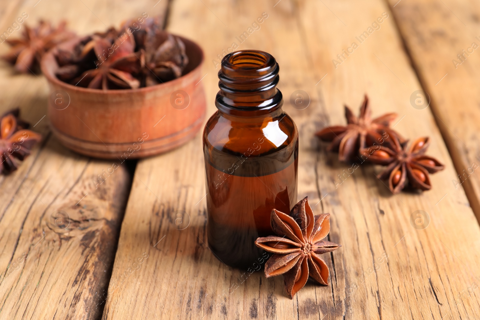 Photo of Bottle of essential oil and anise on wooden table