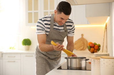 Photo of Handsome man cooking pasta on stove in kitchen