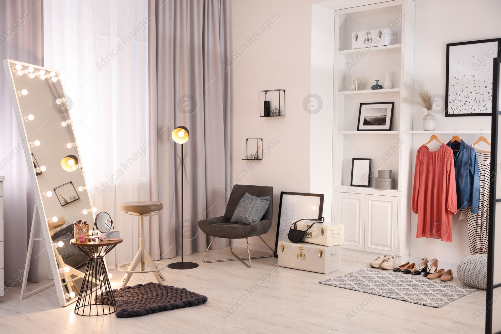 Photo of Makeup room. Stylish mirror with light bulbs, beauty products on table and chair indoors