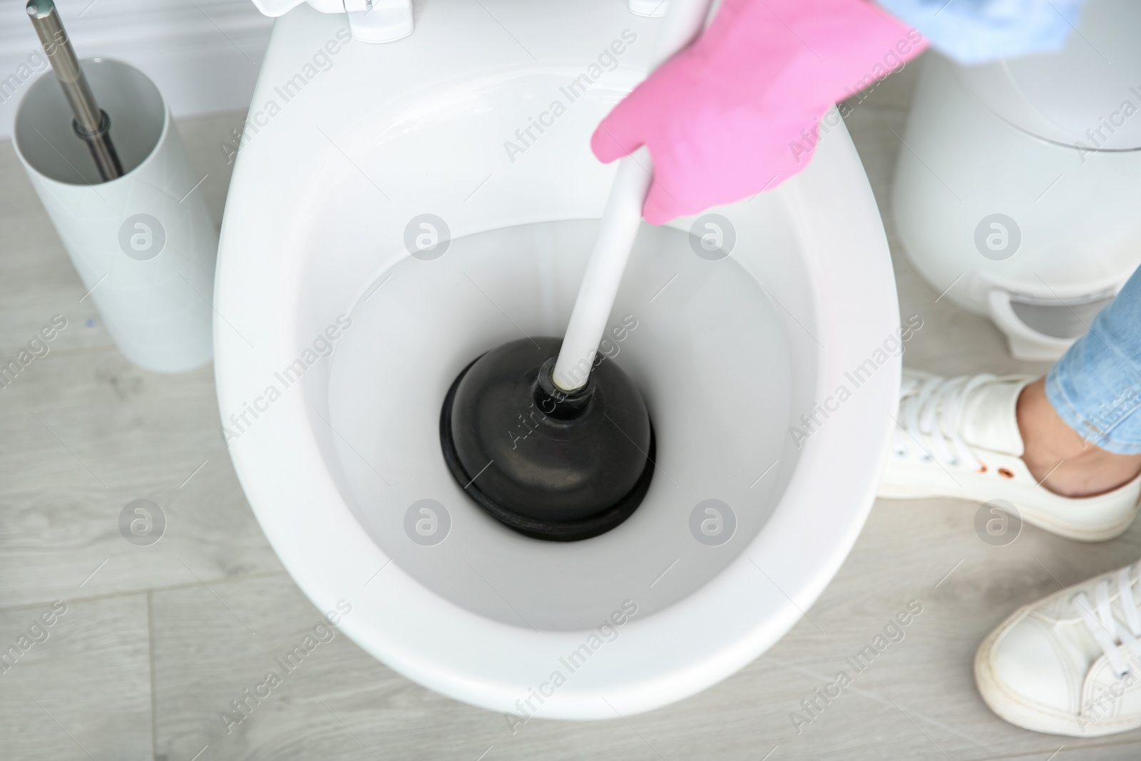 Photo of Woman cleaning toilet bowl in bathroom