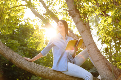 Young woman reading book on tree in park