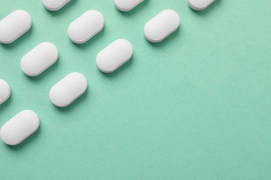 Photo of Many white pills on green background, flat lay. Space for text