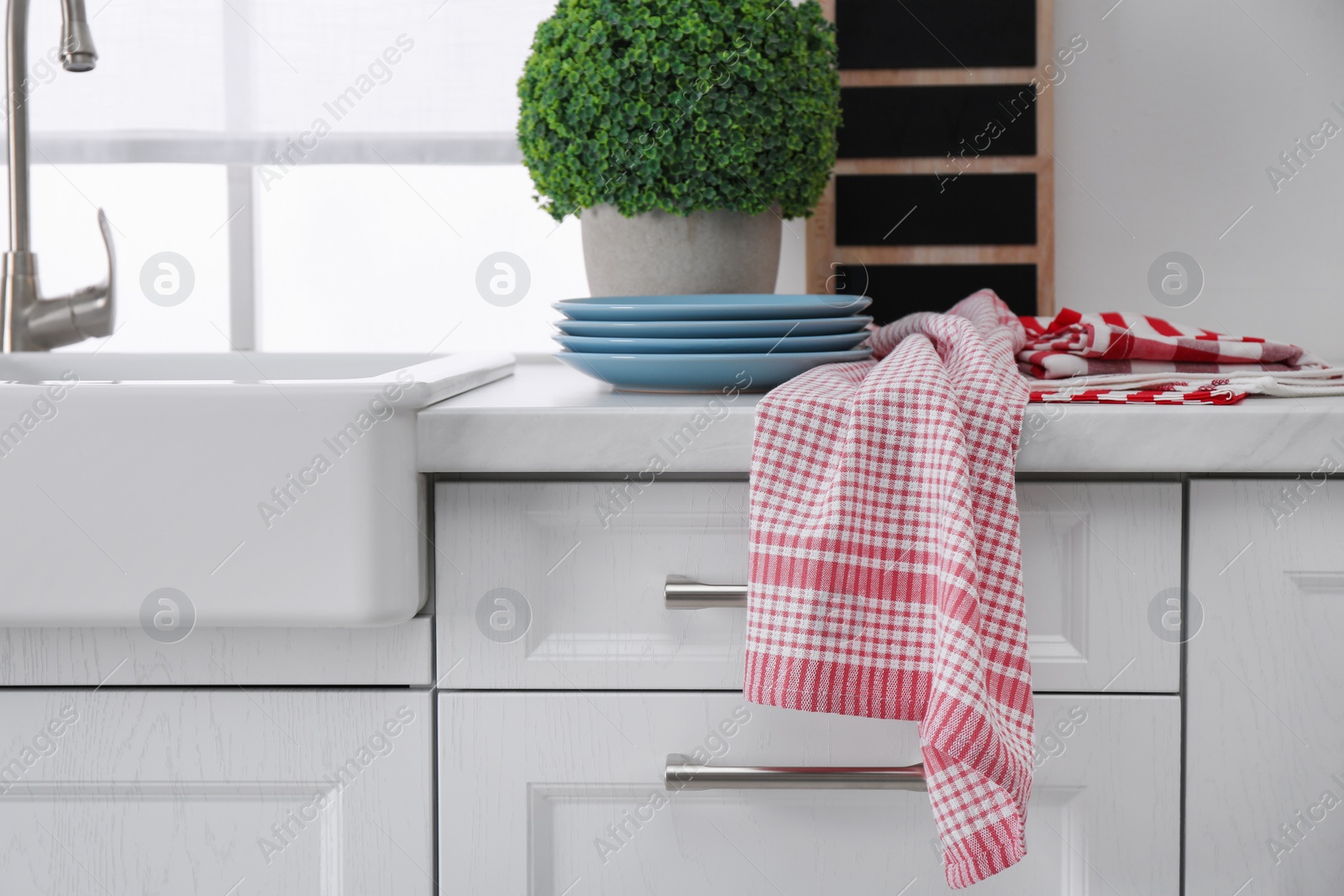 Photo of Different towels and stack of plates near sink on kitchen counter