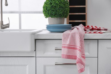 Different towels and stack of plates near sink on kitchen counter