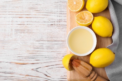Photo of Freshly squeezed lemon juice and squeezer on wooden table, top view. Space for text