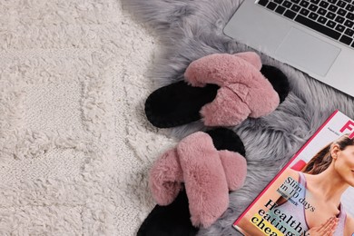 Photo of Soft slippers, magazine and laptop on carpet, top view. Space for text