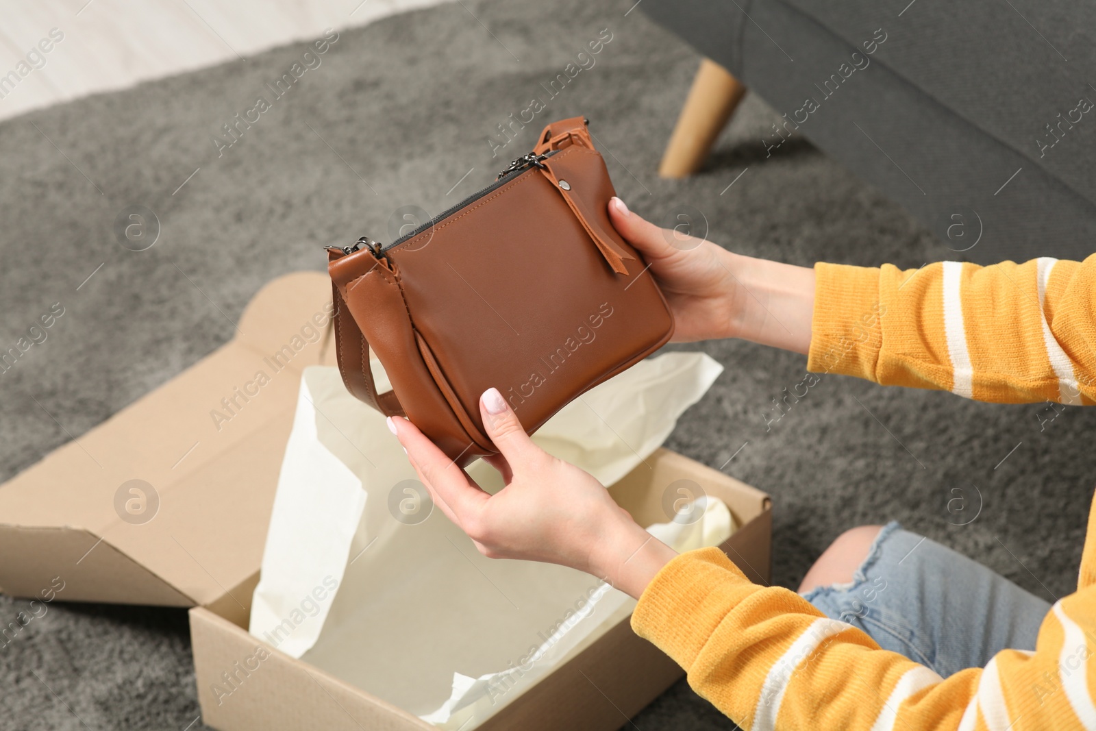 Photo of Woman with just unpacked new bag at home, closeup. Online store