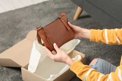 Photo of Woman with just unpacked new bag at home, closeup. Online store
