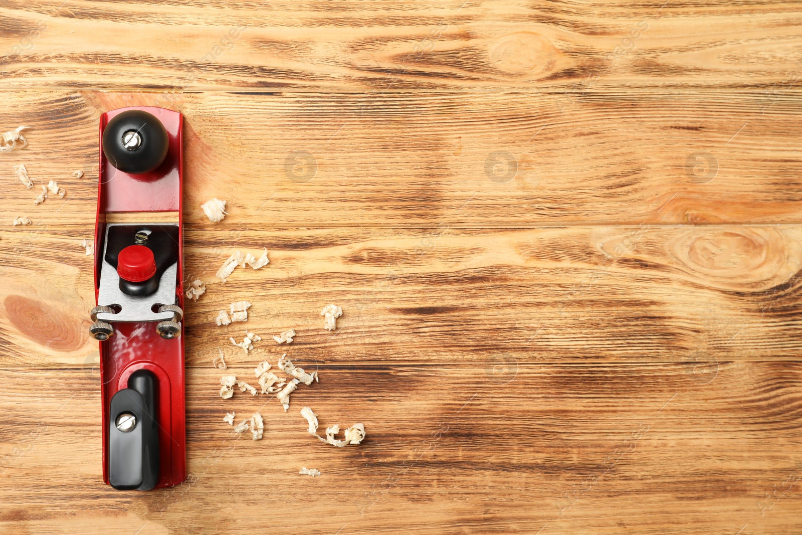 Photo of Modern jack plane and shavings on wooden background, top view with space for text. Carpenter's tool