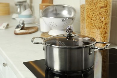 Shiny pot on electric stove in kitchen. Cooking utensil