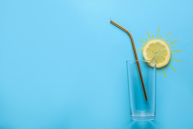 Photo of Composition of citrus slice as sun, straw and glass on color background, top view with space for text. Summer cocktail