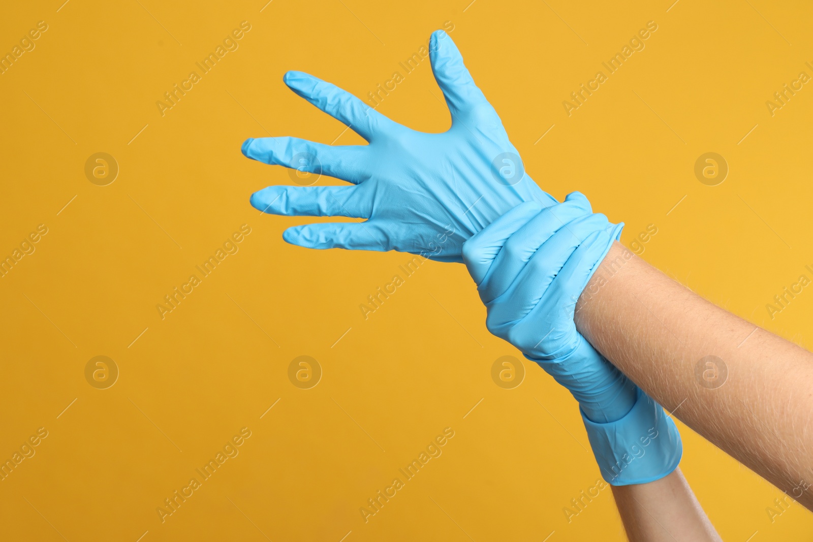 Photo of Doctor wearing medical gloves on yellow background, closeup. Space for text