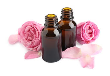 Photo of Aroma oil bottles with pink roses on white background