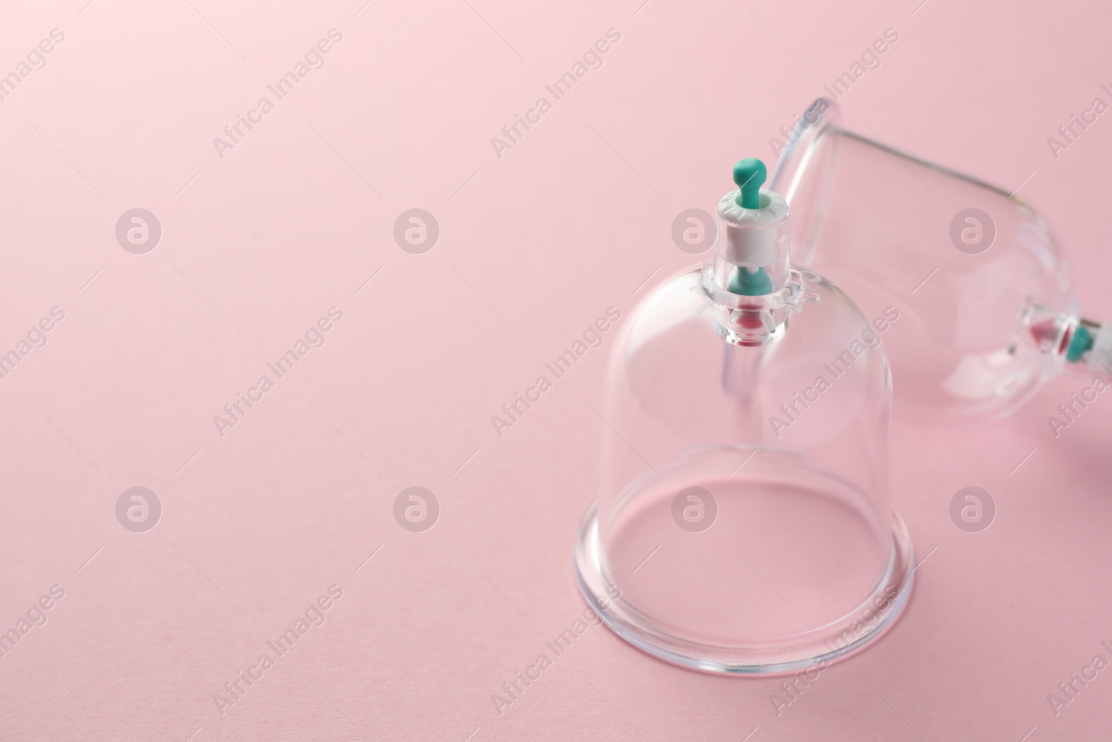 Photo of Plastic cups on pink background, space for text. Cupping therapy