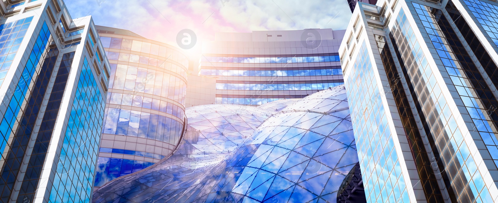 Image of Beautiful blue sky with clouds reflecting in windows, banner design. Low angle view of modern buildings on sunny day