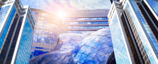 Image of Beautiful blue sky with clouds reflecting in windows, banner design. Low angle view of modern buildings on sunny day