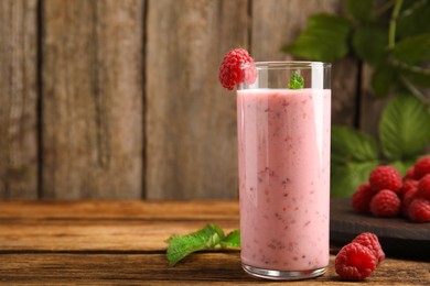 Photo of Glass of tasty fresh raspberry smoothie on wooden table, space for text