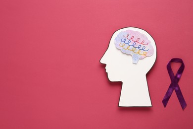 Photo of Human head cutout with brain near purple ribbon on crimson background, flat lay. Epilepsy awareness