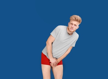Photo of Young man suffering from pain on blue background, space for text. Urology problems