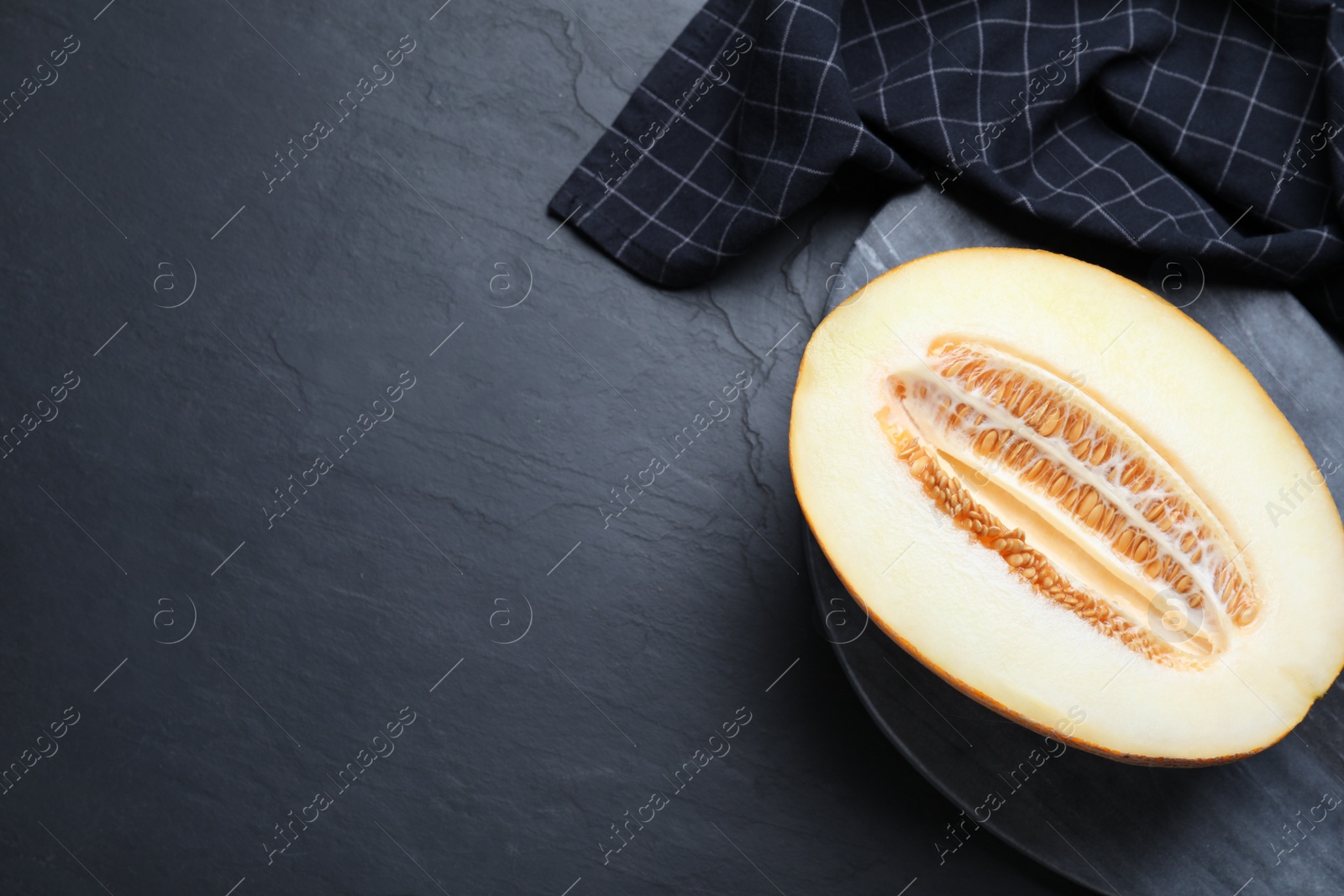 Photo of Delicious honey melon on black table, top view. Space for text