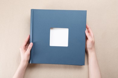 Woman with photo album at color background, top view