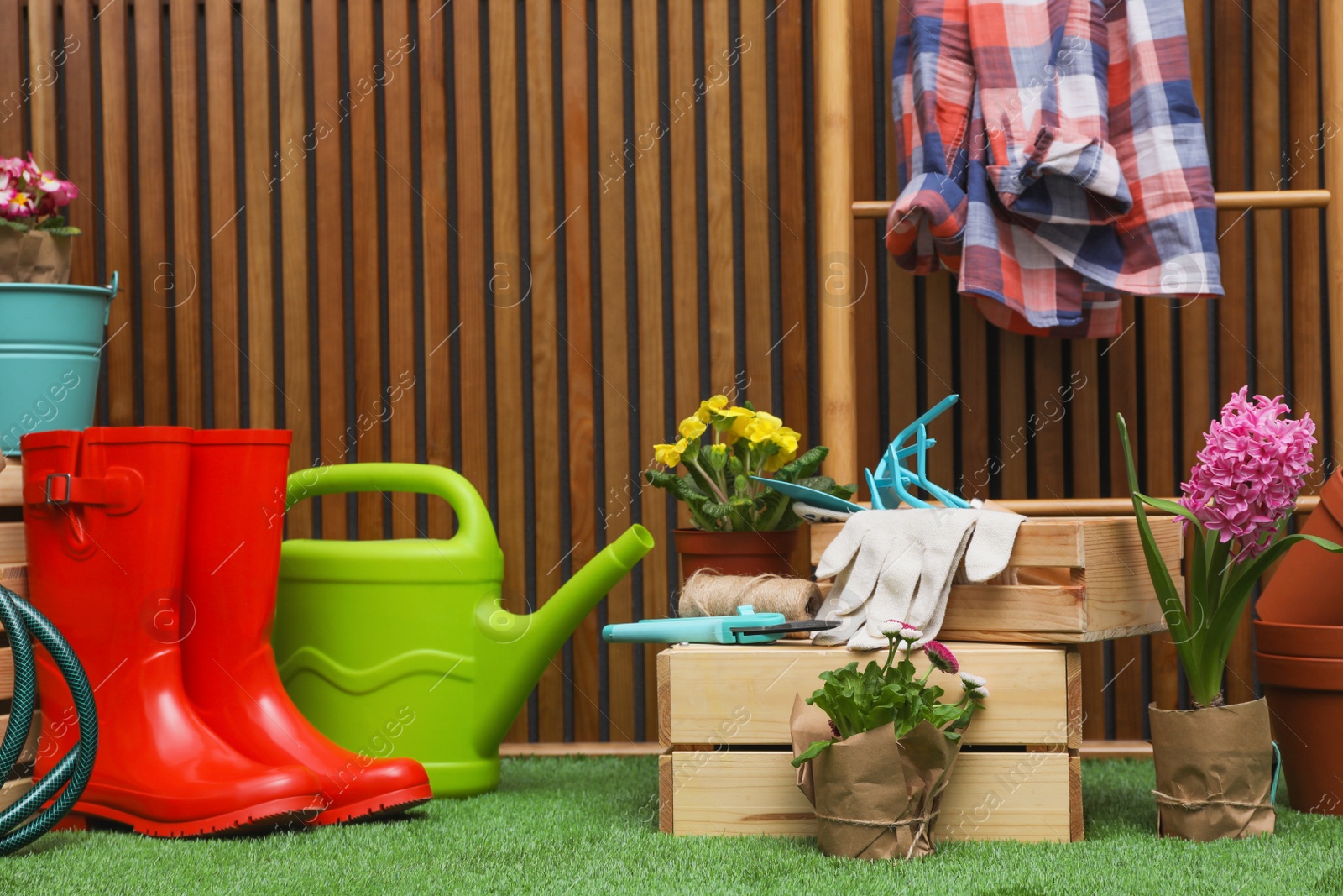 Photo of Composition with different gardening tools on artificial grass at wooden wall