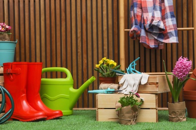 Composition with different gardening tools on artificial grass at wooden wall