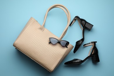 Stylish woman's bag, sunglasses and shoes on beige background, flat lay