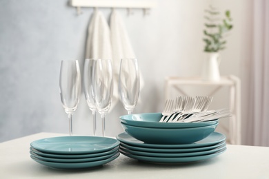 Photo of Set of clean dishware, cutlery and champagne glasses on white table indoors