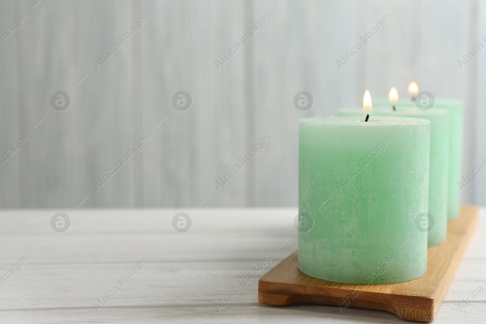 Photo of Bamboo plate with three burning candles on table, space for text