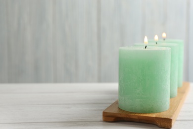 Photo of Bamboo plate with three burning candles on table, space for text