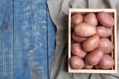 Photo of Crate with fresh ripe organic potatoes on wooden background, top view