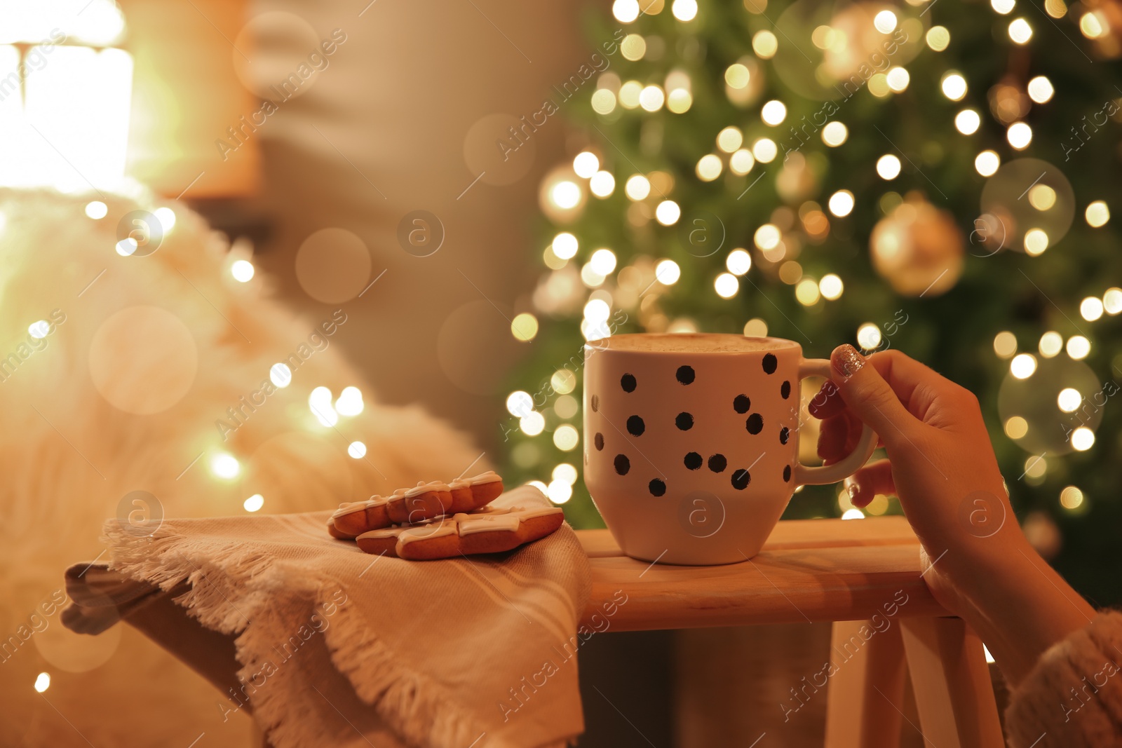 Photo of Woman with cup of hot drink and Christmas cookies at home, closeup