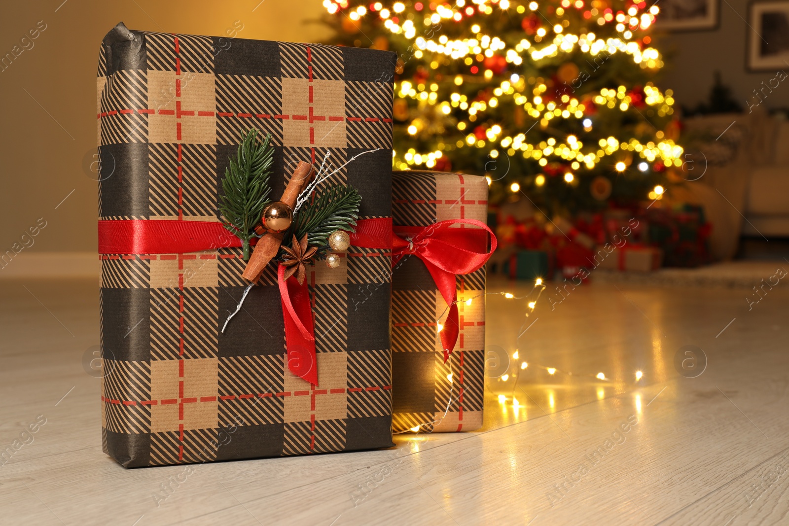 Photo of Beautiful gift boxes against fir tree with Christmas lights at home