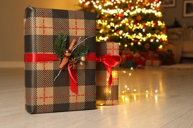 Beautiful gift boxes against fir tree with Christmas lights at home