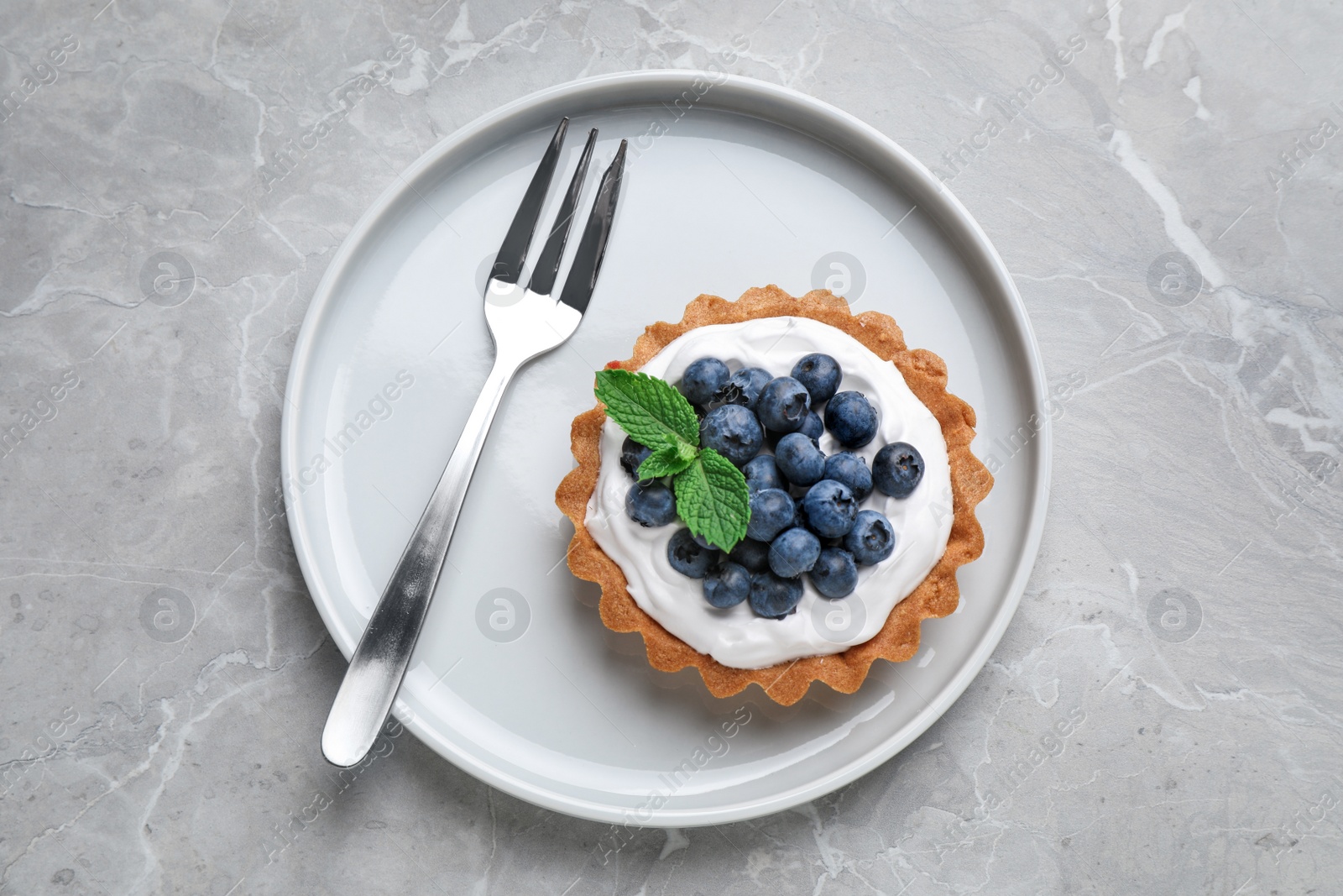 Photo of Tart with blueberries served on marble table, top view. Delicious pastries