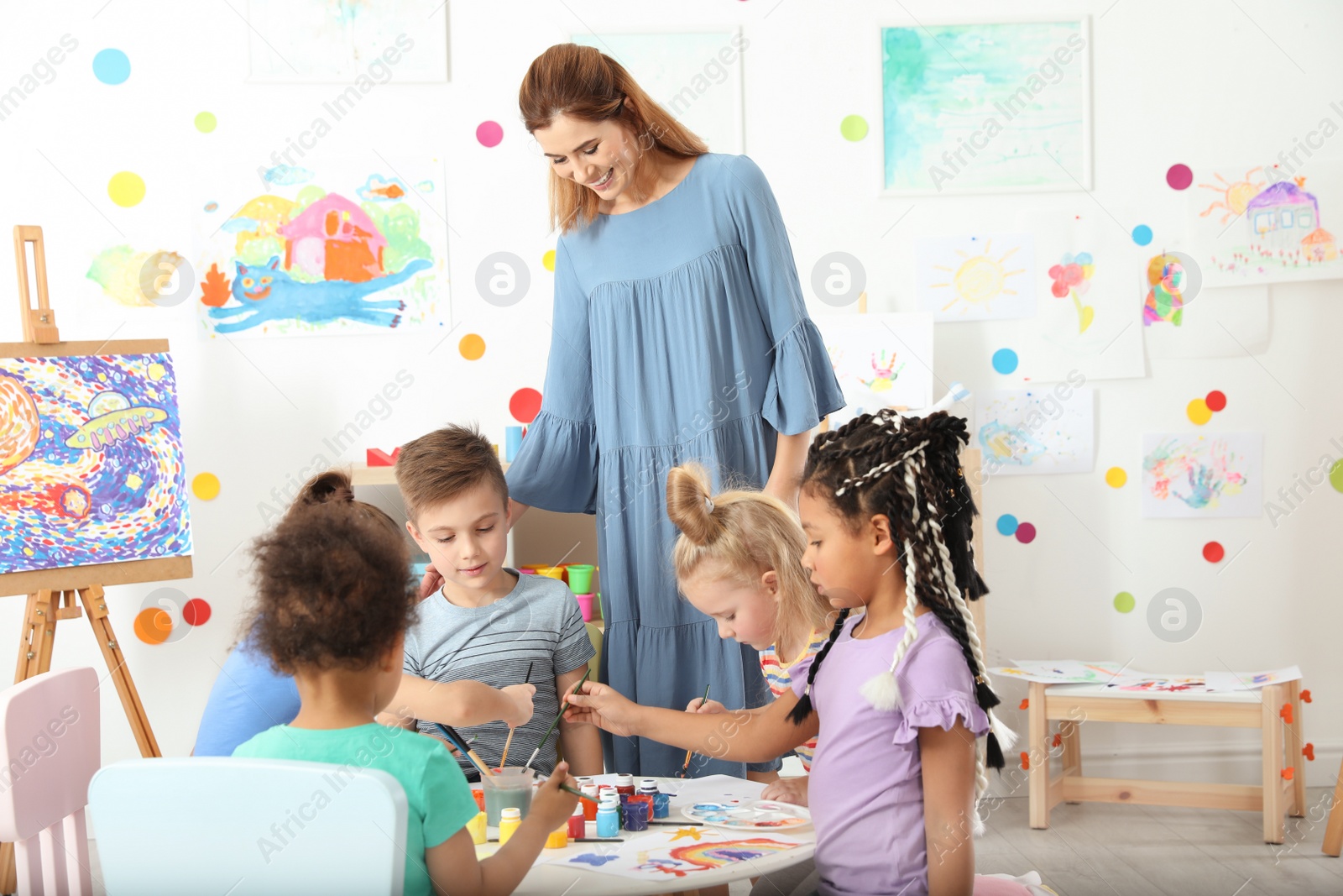 Photo of Children with female teacher at painting lesson indoors