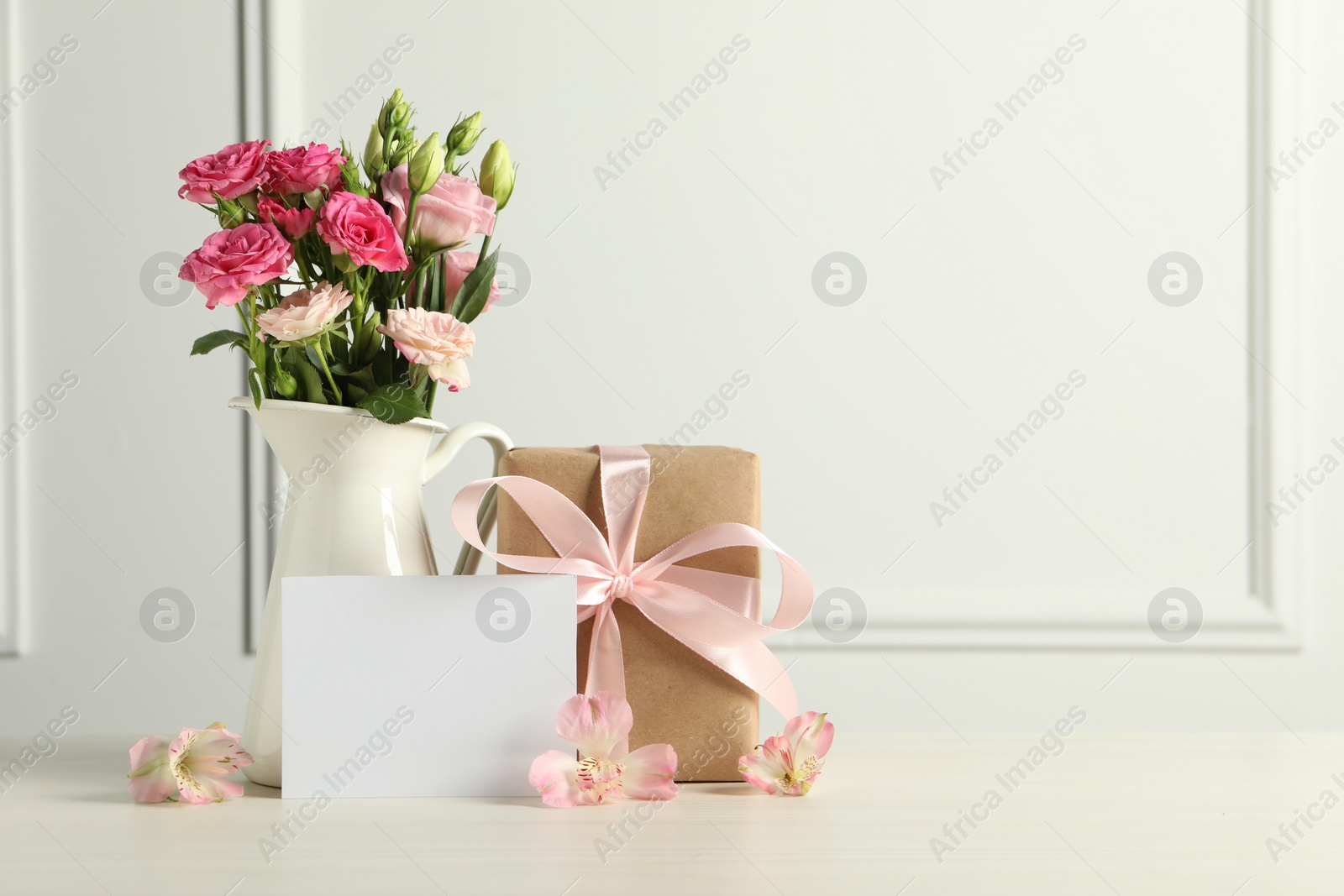 Photo of Happy Mother's Day. Gift box, blank card and beautiful flowers on white table. Space for text